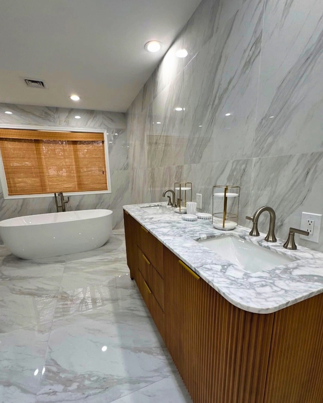 Bathroom we remodeled with marble walls and floor, a freestanding tub and a fluted wood double vanity