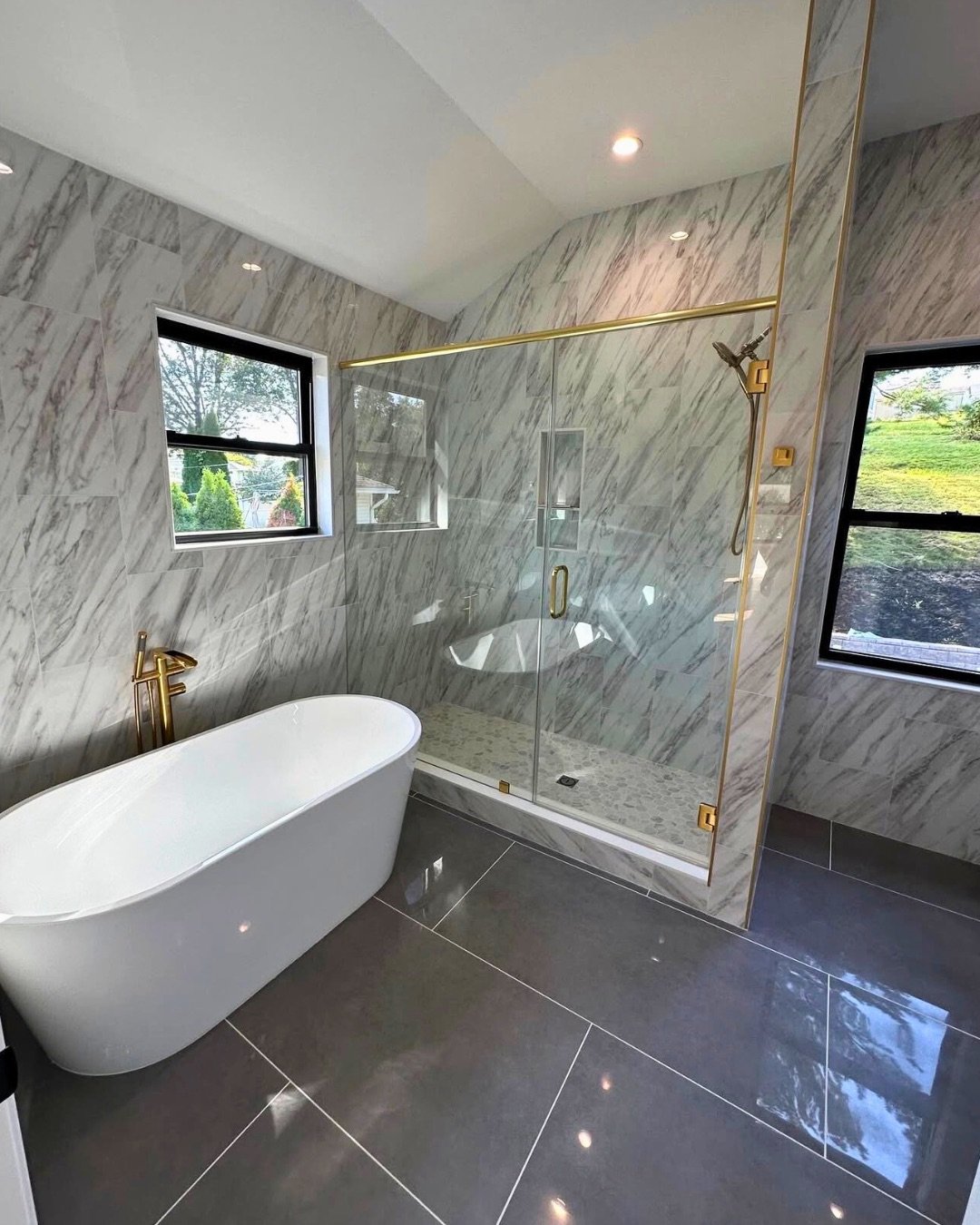 Bathroom we remodeled with marble walls, a freestanding tub and a glass shower with gold fixtures